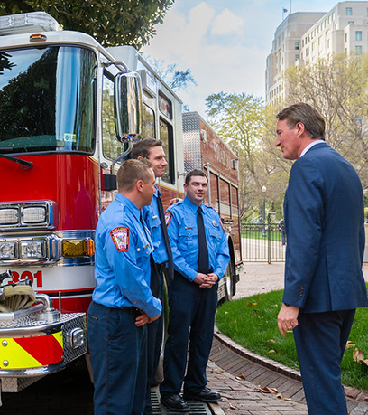 फायर ट्रक के सामने खड़े तीन फायरमैन और गवर्नर